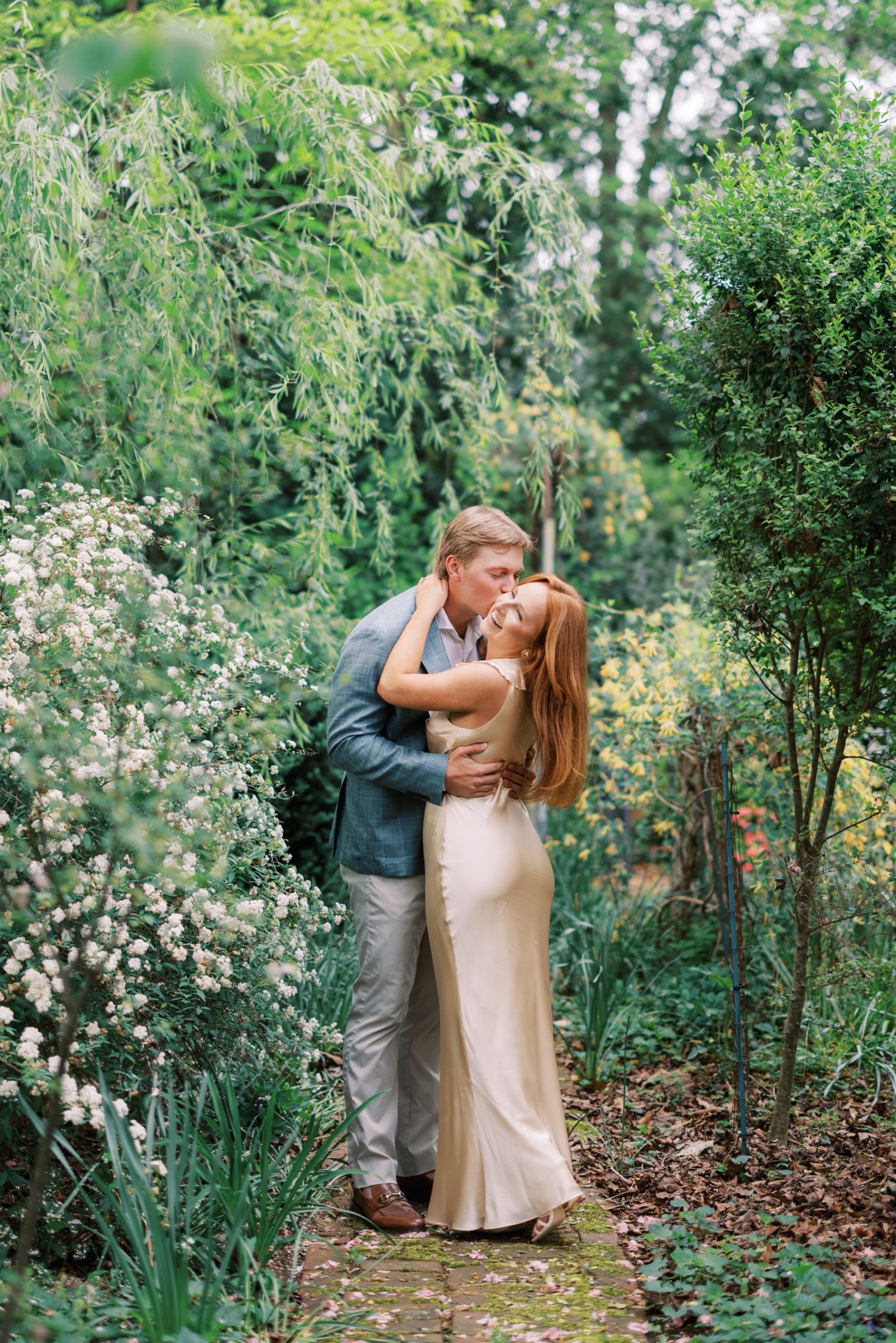 guy kisses his fiancé in garden 