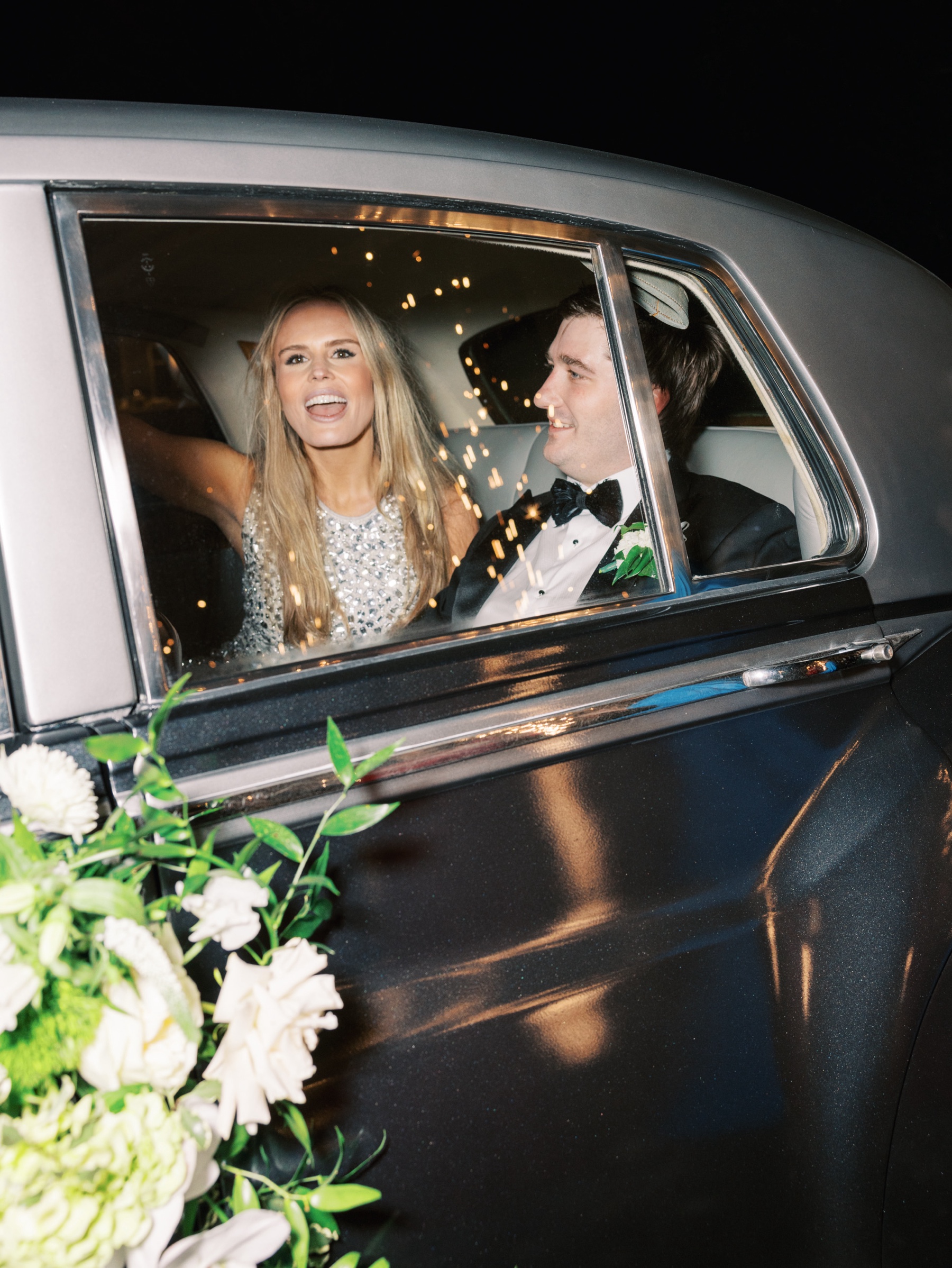 Bride and groom exit in classic car 