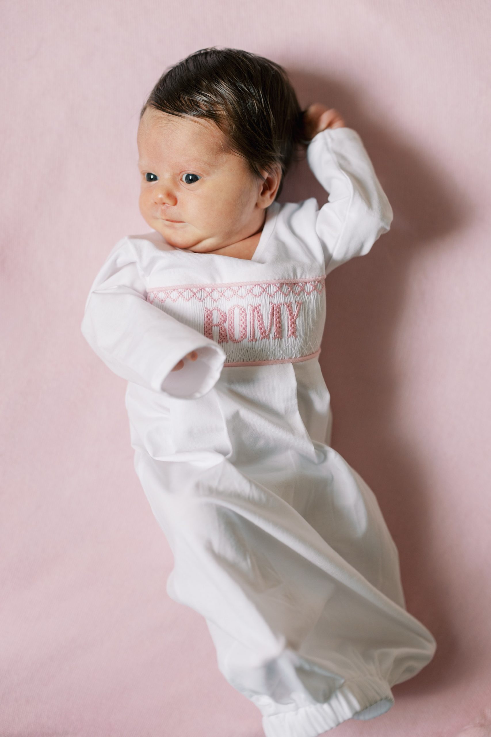 newborn girl lays on pink blanket