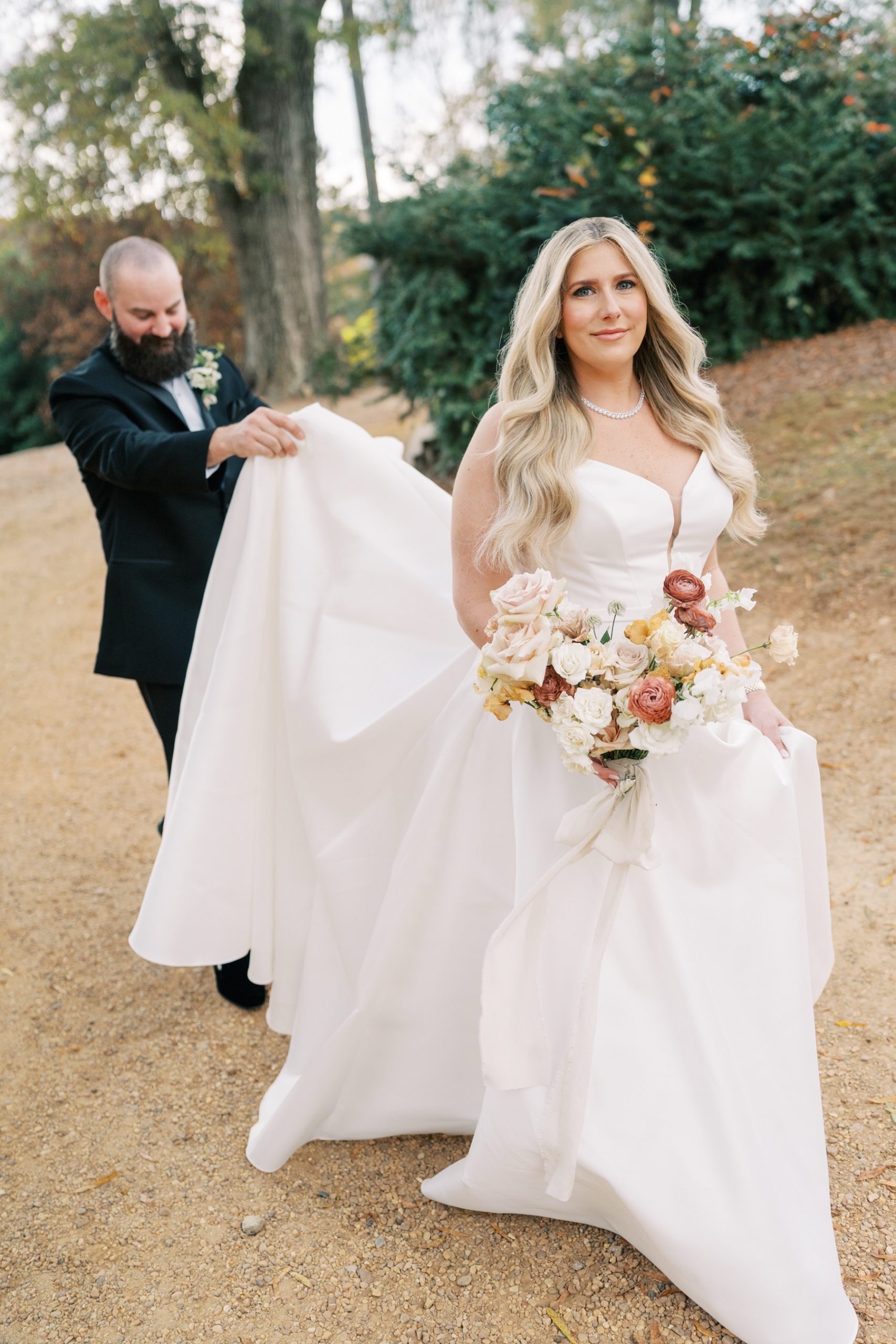 Bride and groom walking with groom carrying her train