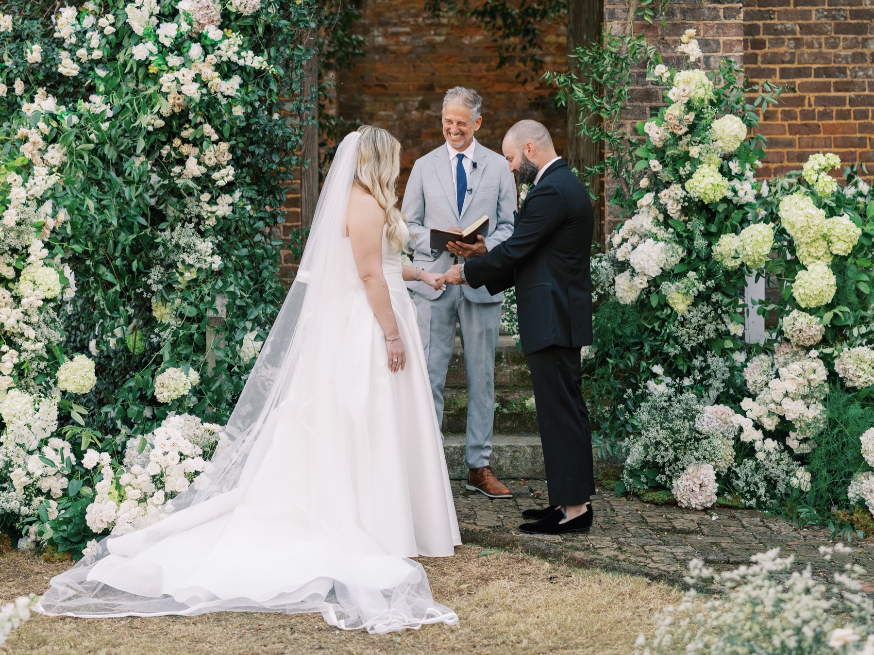 Bride and groom exchanging rings surrounded by white flowers at the Barnsley Resort