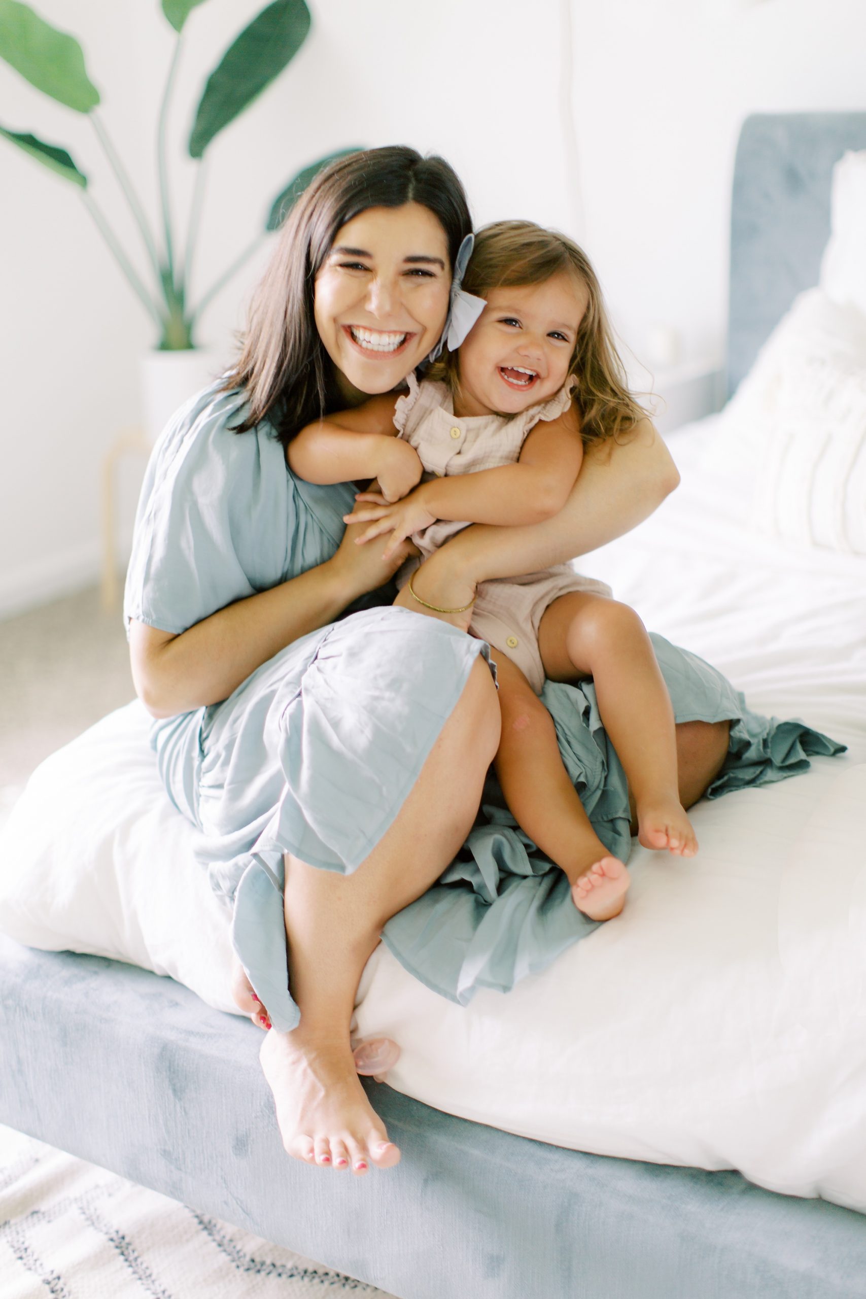 mom poses with daughter on bed at home