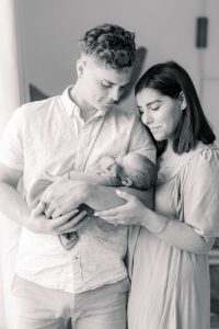 new parents look at baby boy by window