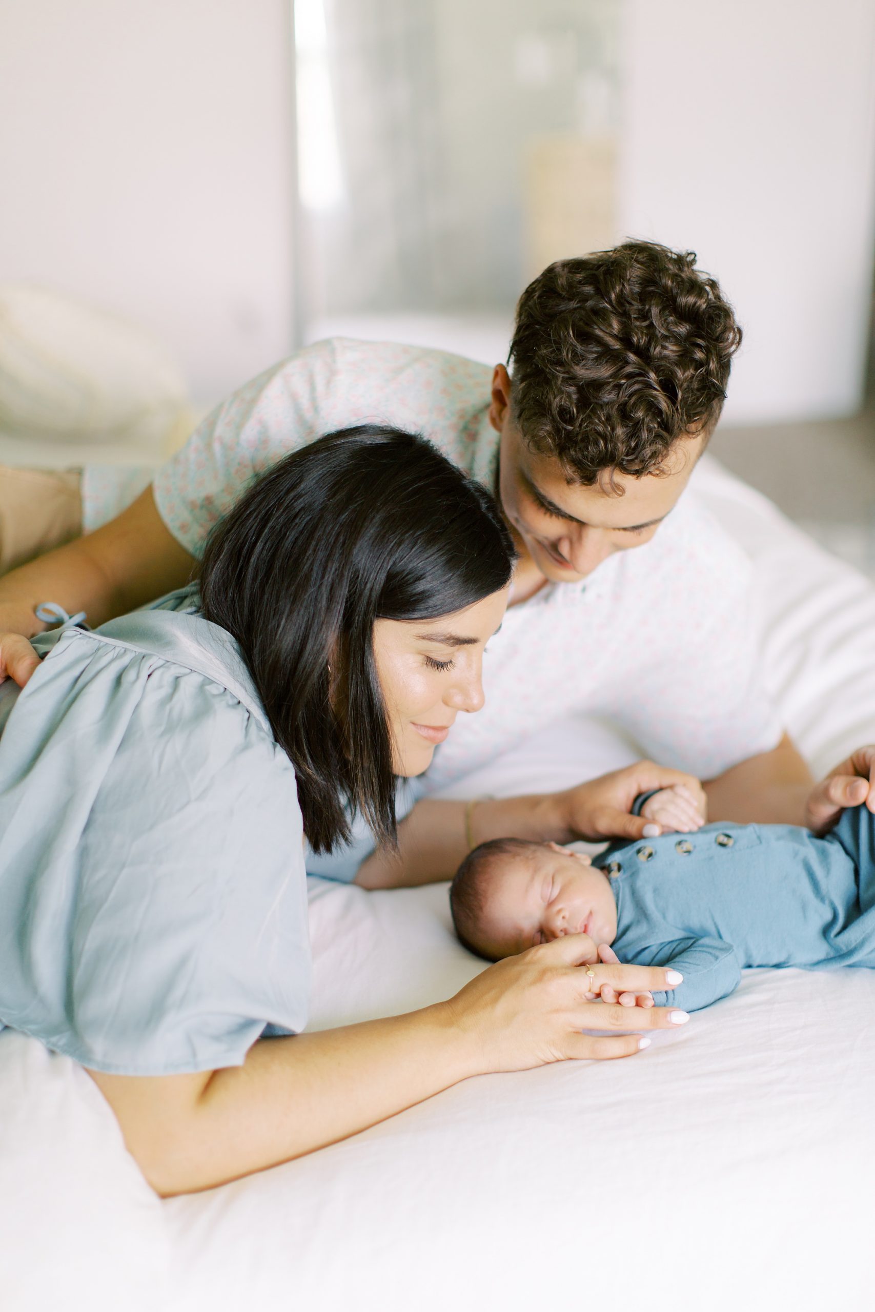 parents lay on bed with newborn baby boy