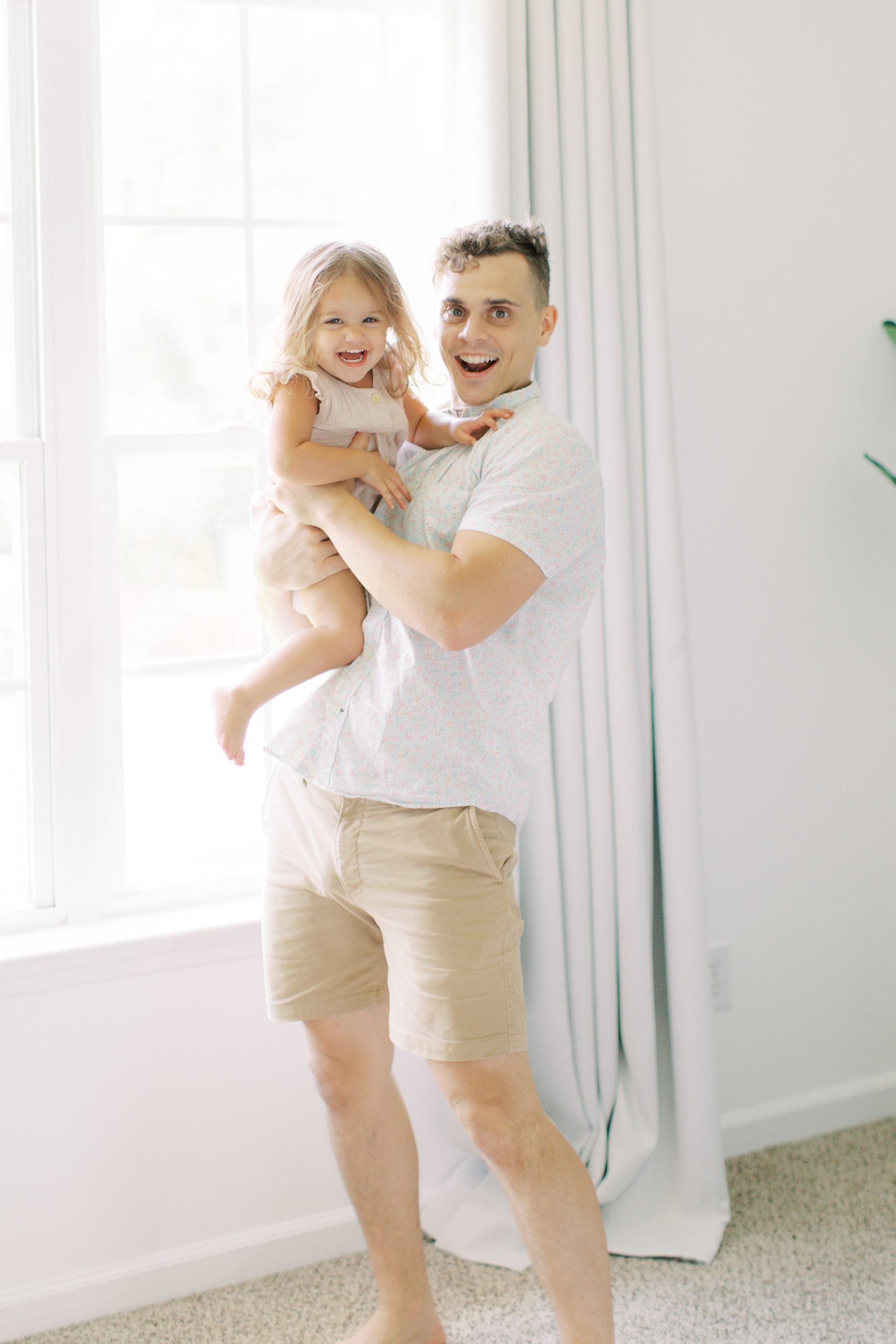 dad plays with toddler during family photos at home