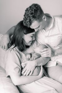 parents snuggle looking at new baby boy