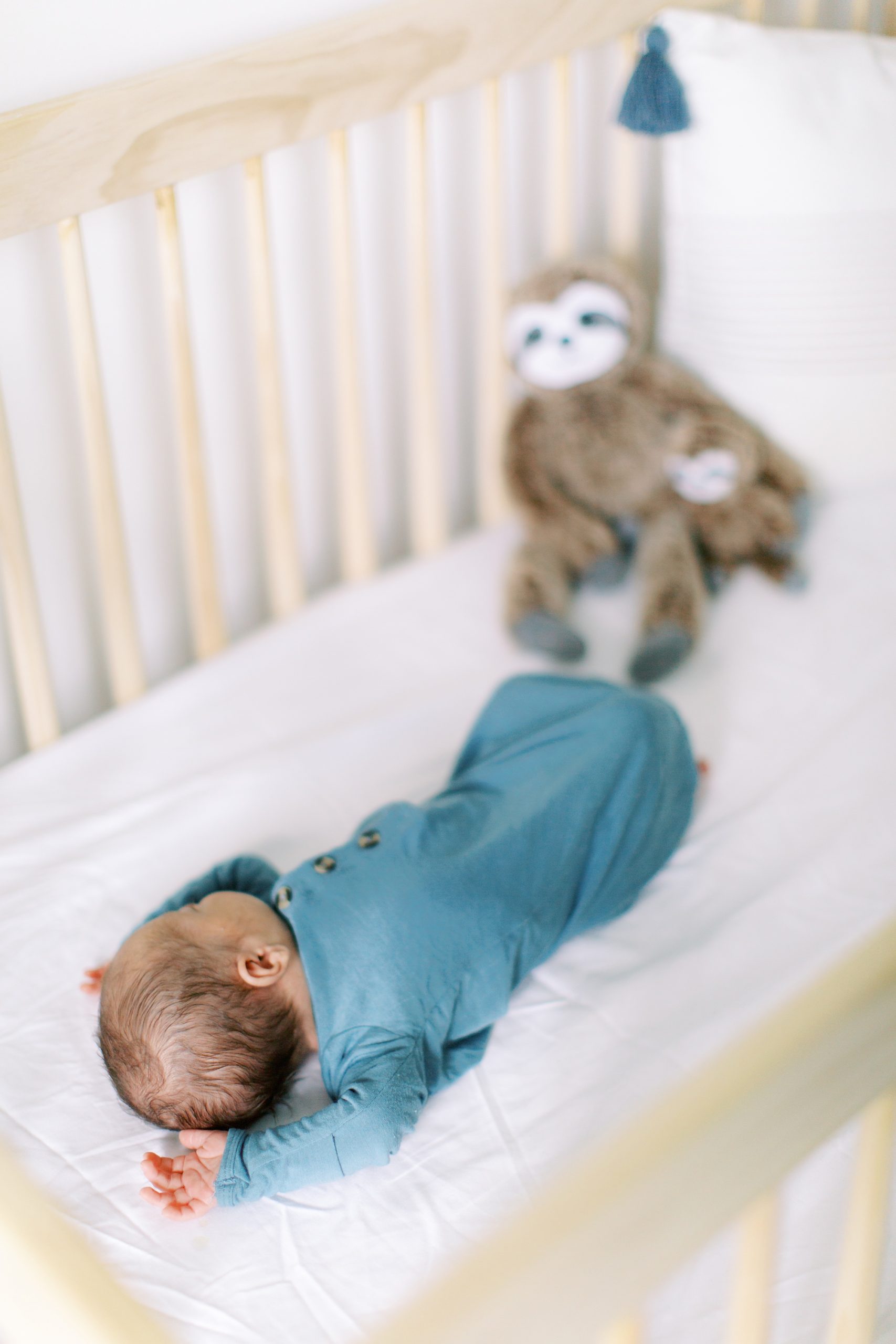 Charlotte lifestyle newborn session with baby laying in crib by sloth
