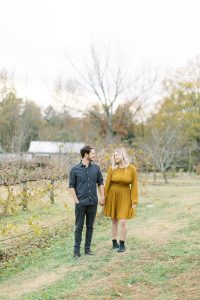 engaged couple walks through field of grapes during North Corner Haven engagement session