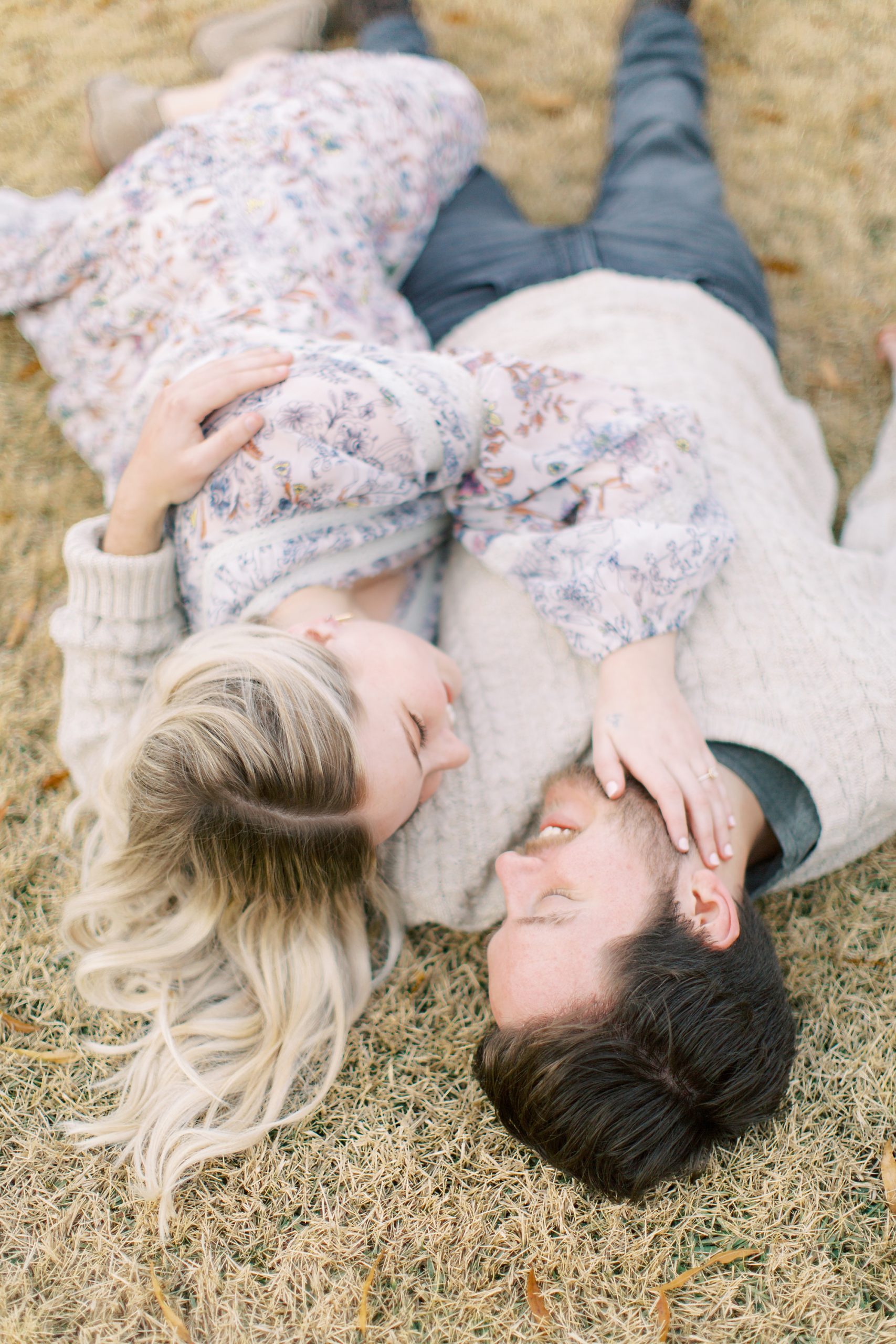 engaged couple lays on grass at North Corner Haven