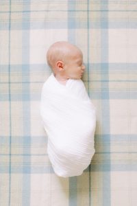 baby lays on yellow and blue plaid tartan during lifestyle newborn session