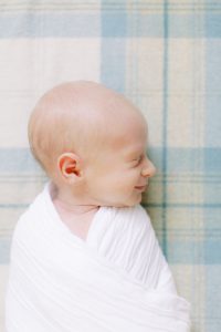 baby smiles laying on tartan during lifestyle newborn photos