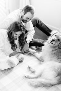 family poses with newborn baby and dog