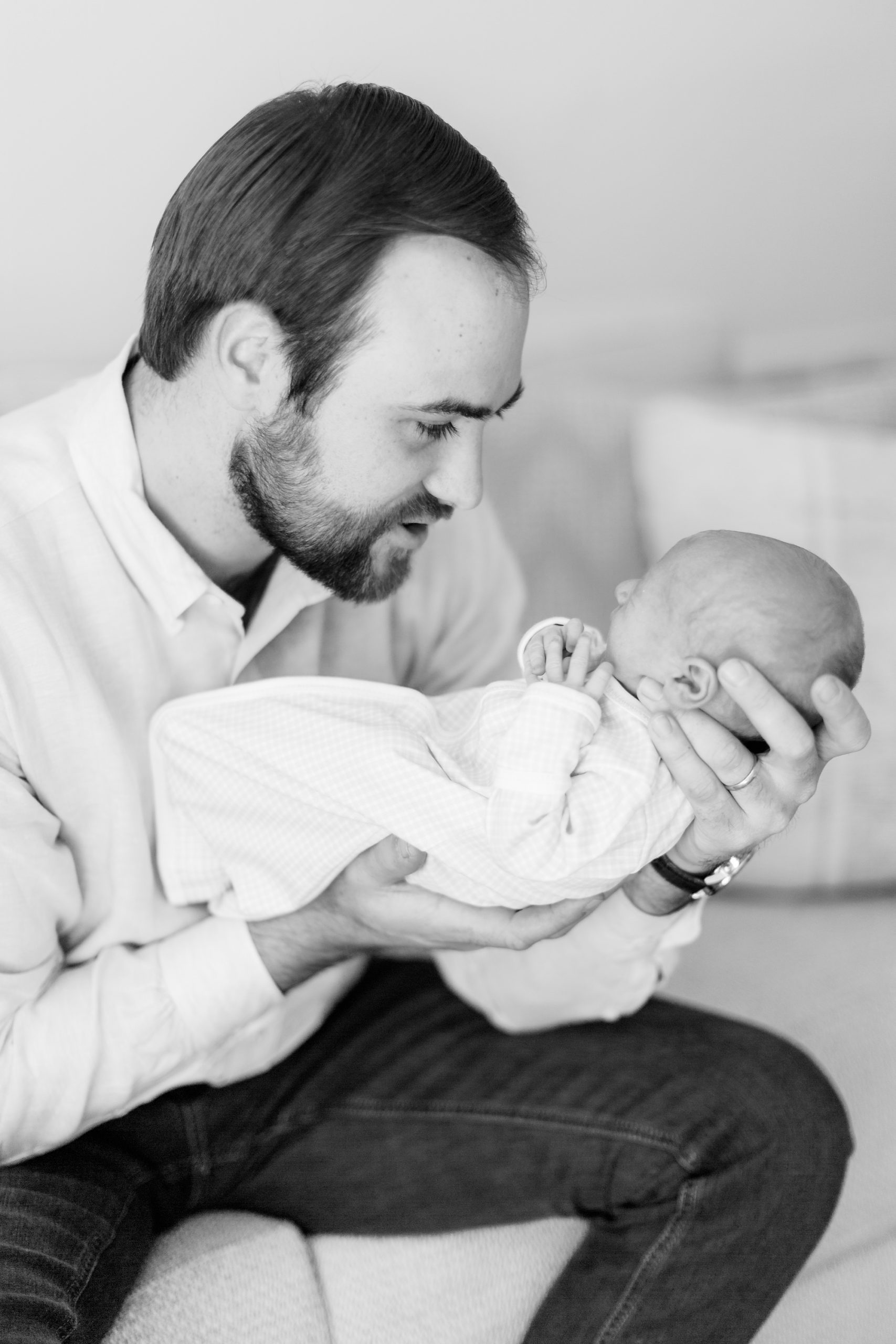 dad holds baby boy in hands during lifestyle photos at home