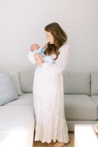mom holds baby boy in living room during portraits at home with Charlotte newborn photographer Demi Mabry