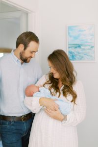 new parents hold baby boy in blue blanket