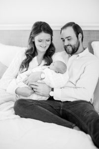 parents sit on bed with newborn baby boy