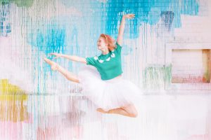 ballerina in green sweater and pink tutu jumps during Uptown Charlotte Branding Session