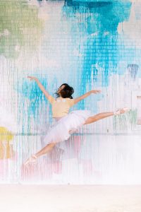 ballerina in tutu and yellow sweater jumps during branding photos