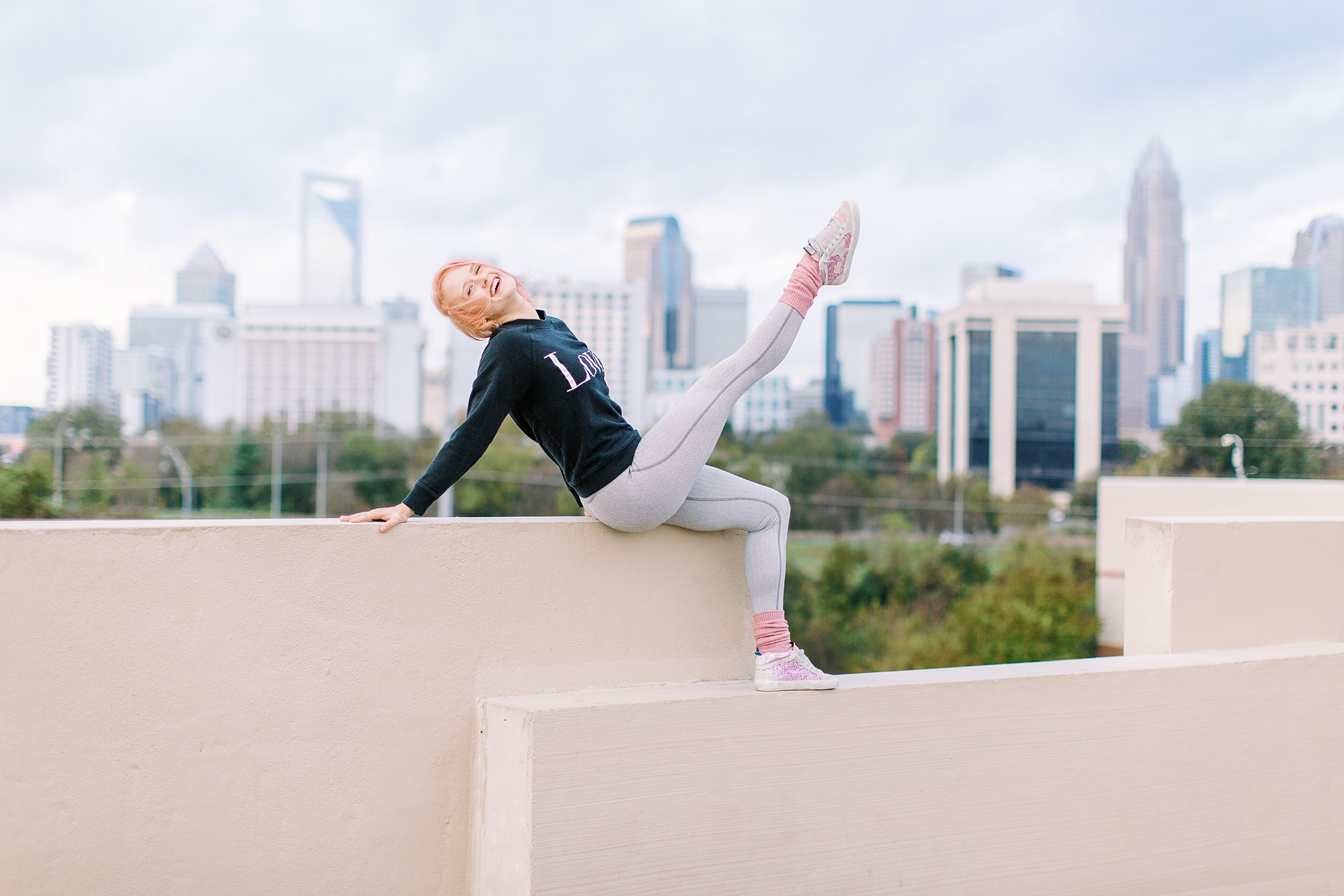 dancer kicks leg in front of Charlotte NC skyline