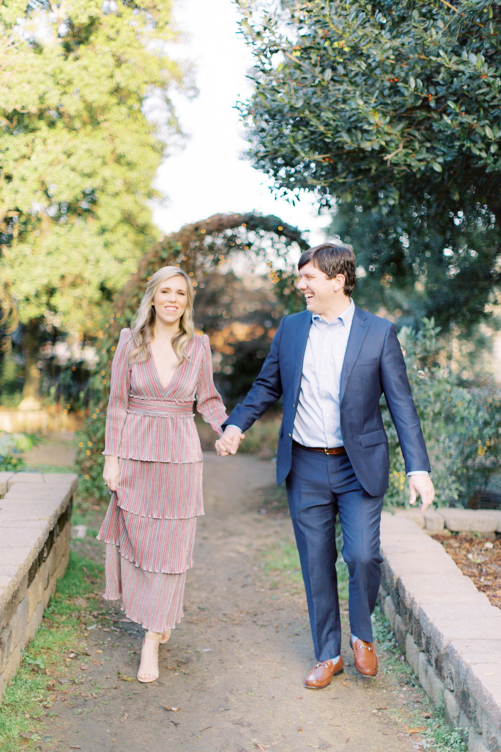 married couple holds hands walking through rose garden boxes