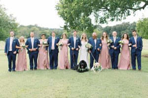 bride and groom pose with bridal party in navy and pink gowns with dogs