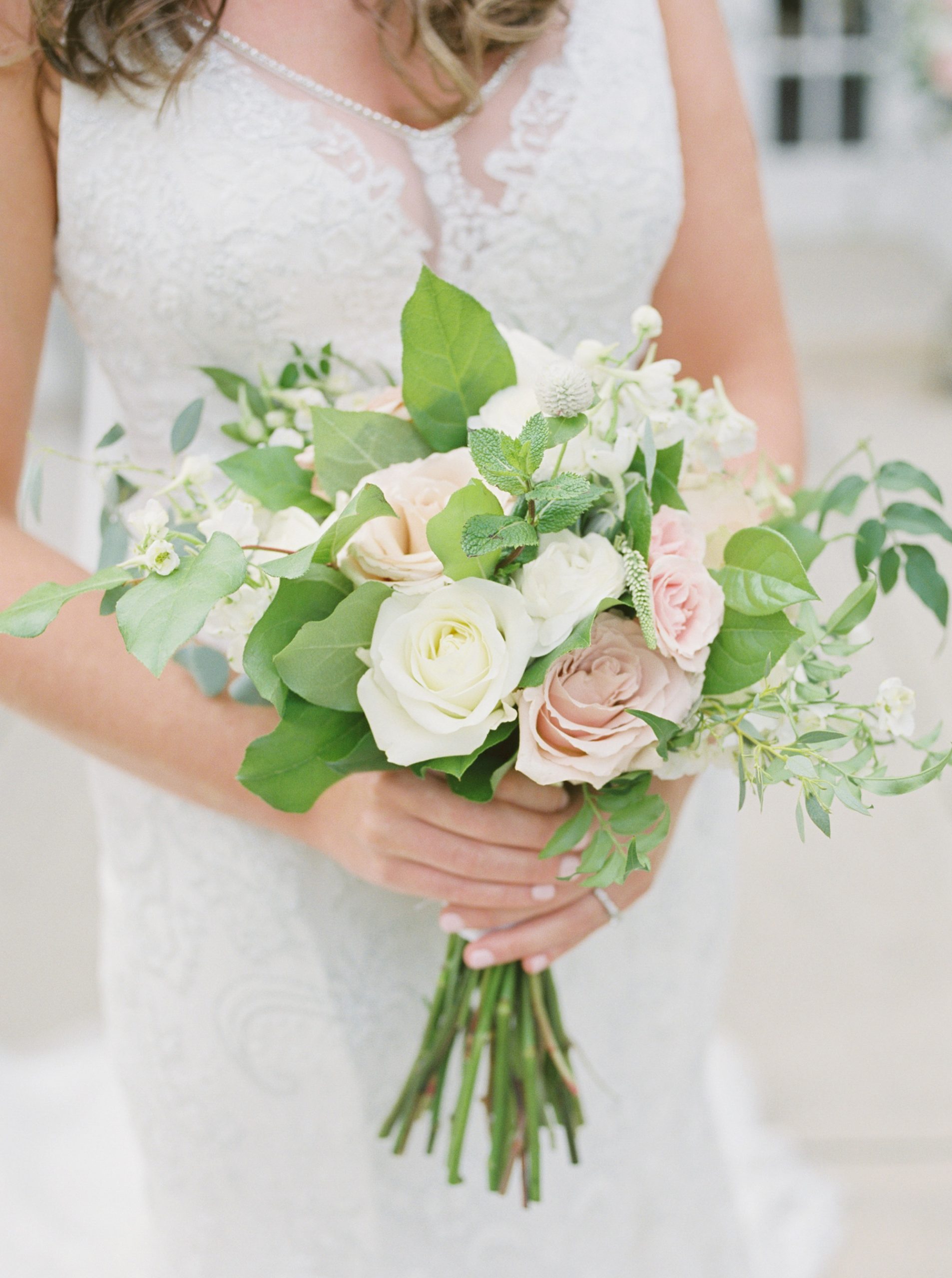 bride holds bouquet of pink and ivory flowers