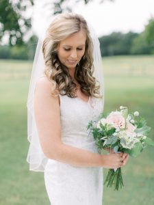bridal holds bouquet of pink flowers outside The Dairy Barn