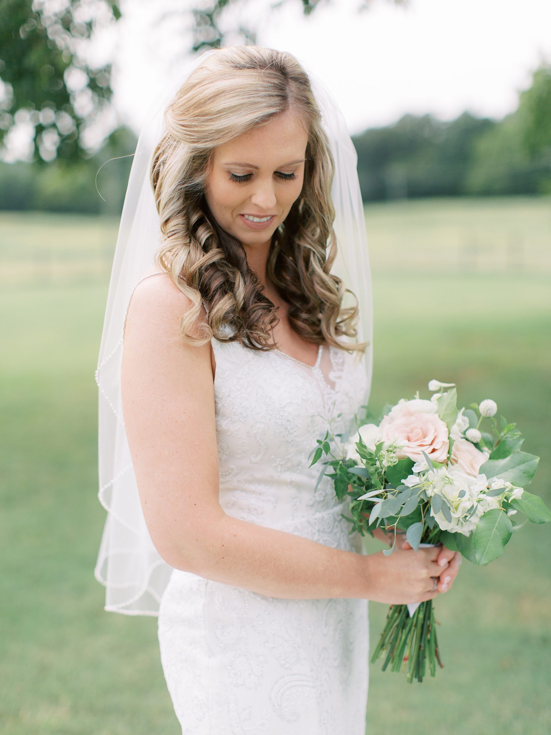 bridal holds bouquet of pink flowers outside The Dairy Barn