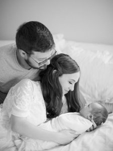 parents look at baby boy during newborn photos at home