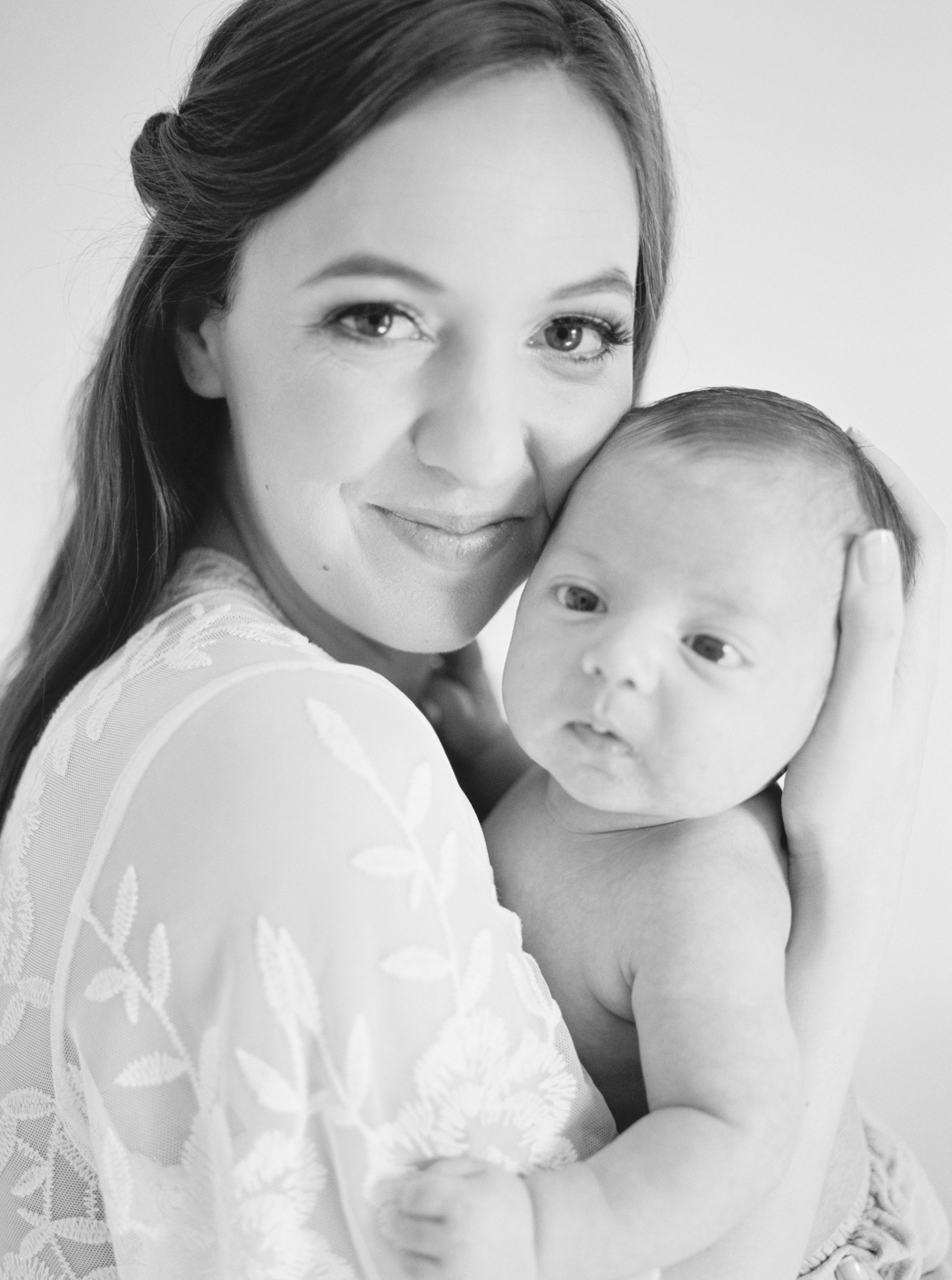 mom holds baby against shoulder during Charlotte newborn session