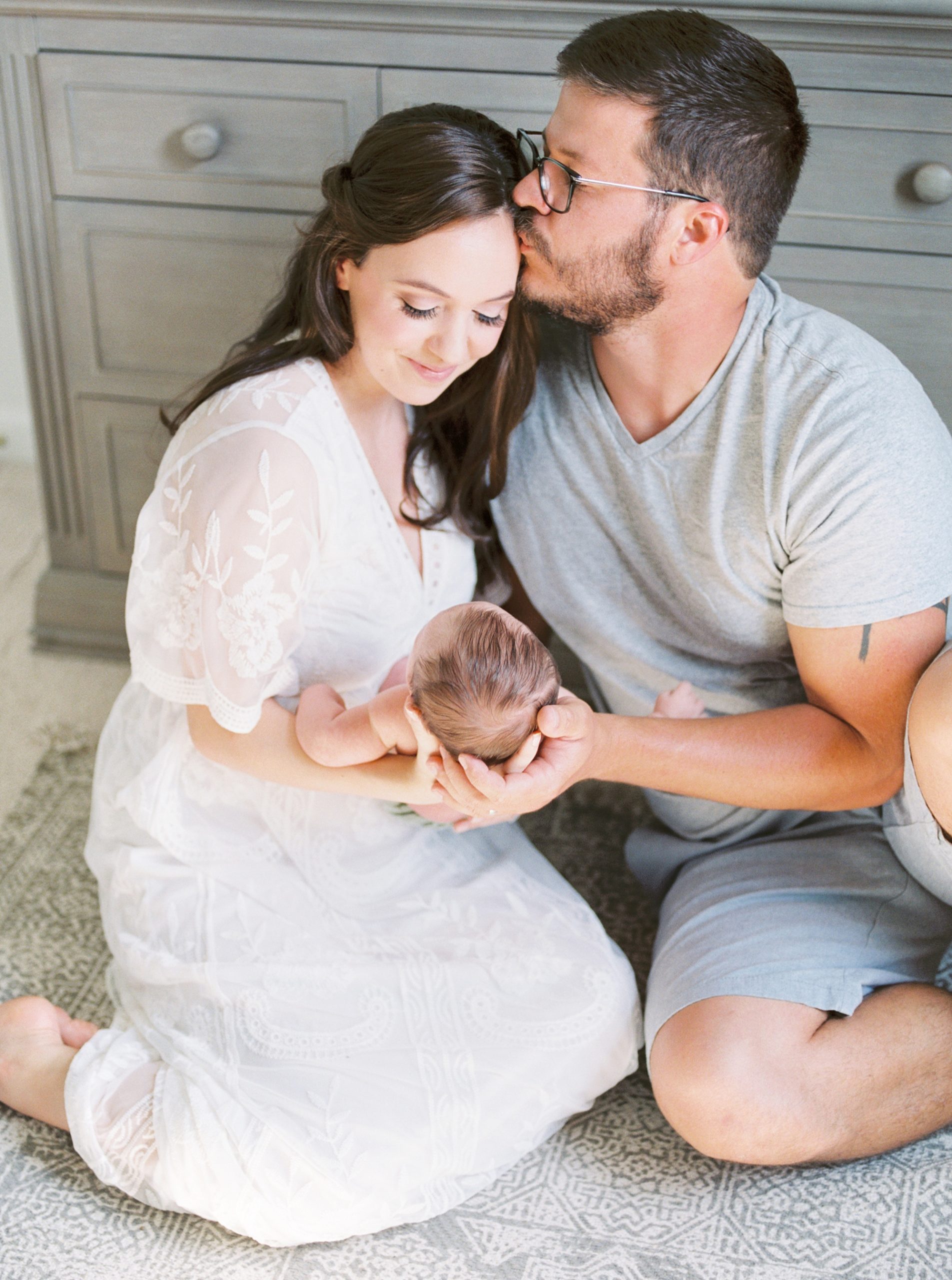 dad kisses mom's forehead during Charlotte newborn session