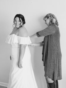 mother helps bride with dress before Charleston microwedding on the beach