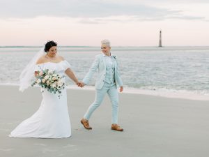 married couple walks along beach at sunset
