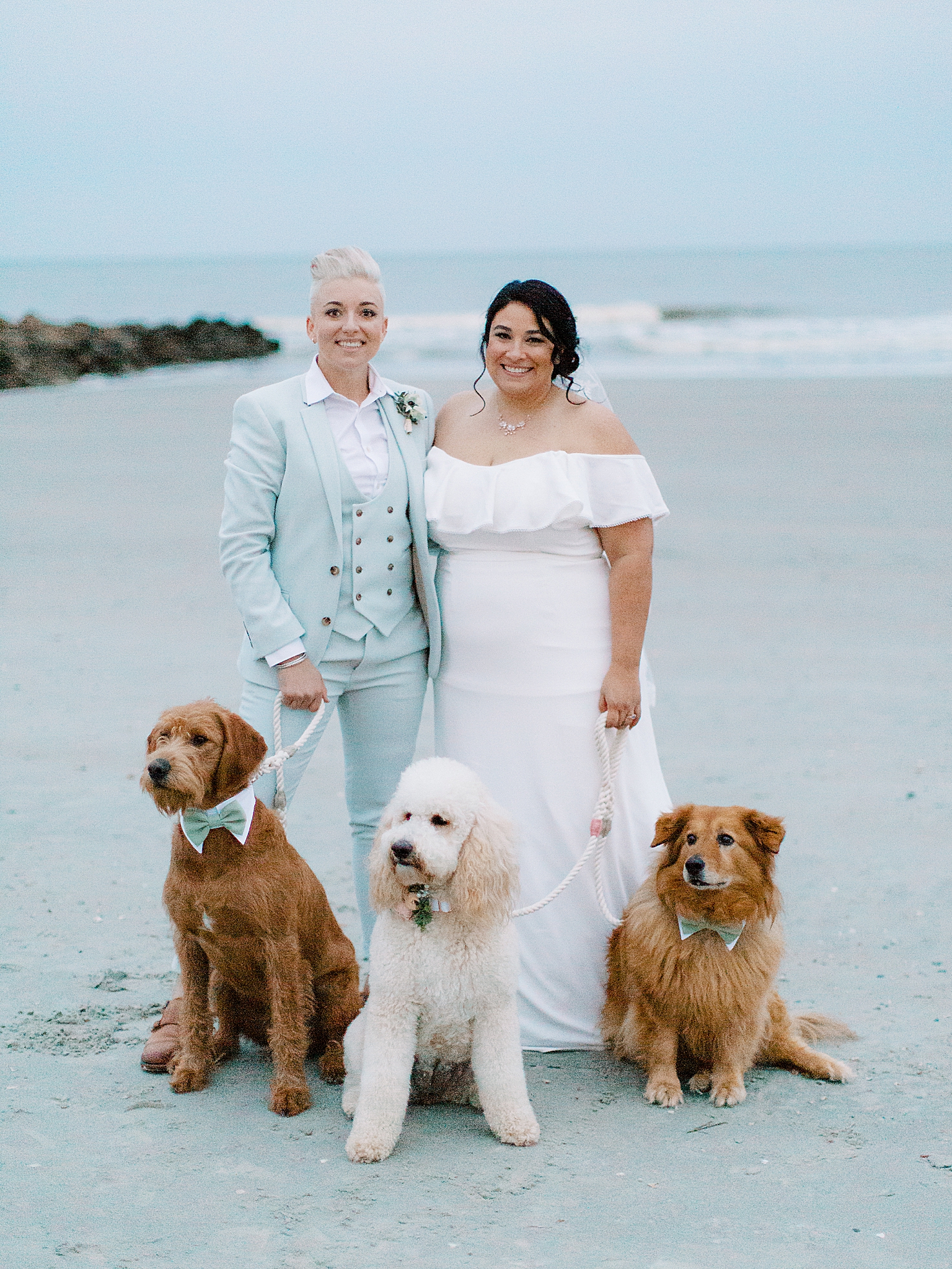 newlyweds pose with three dogs on Charleston beach