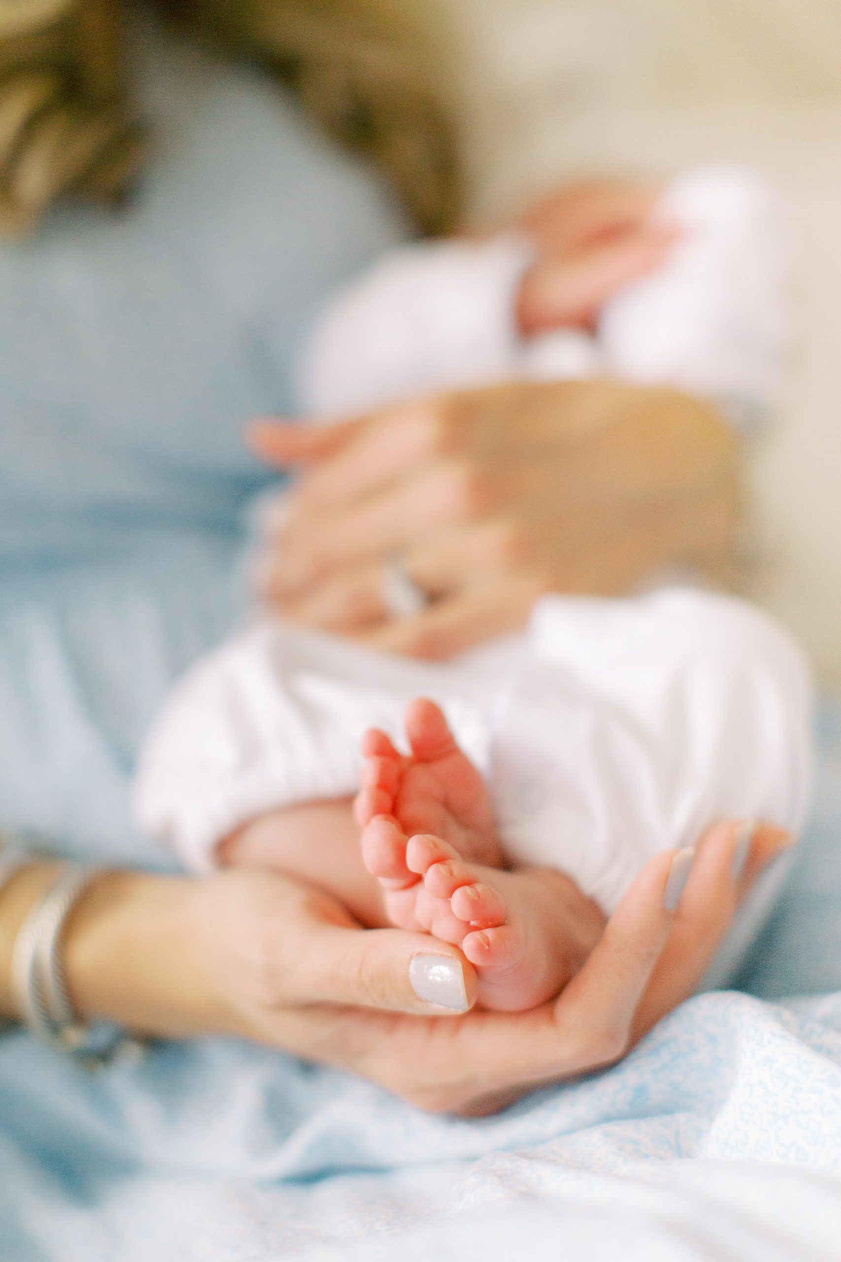 mom cradles baby's feet during lifestyle newborn photos
