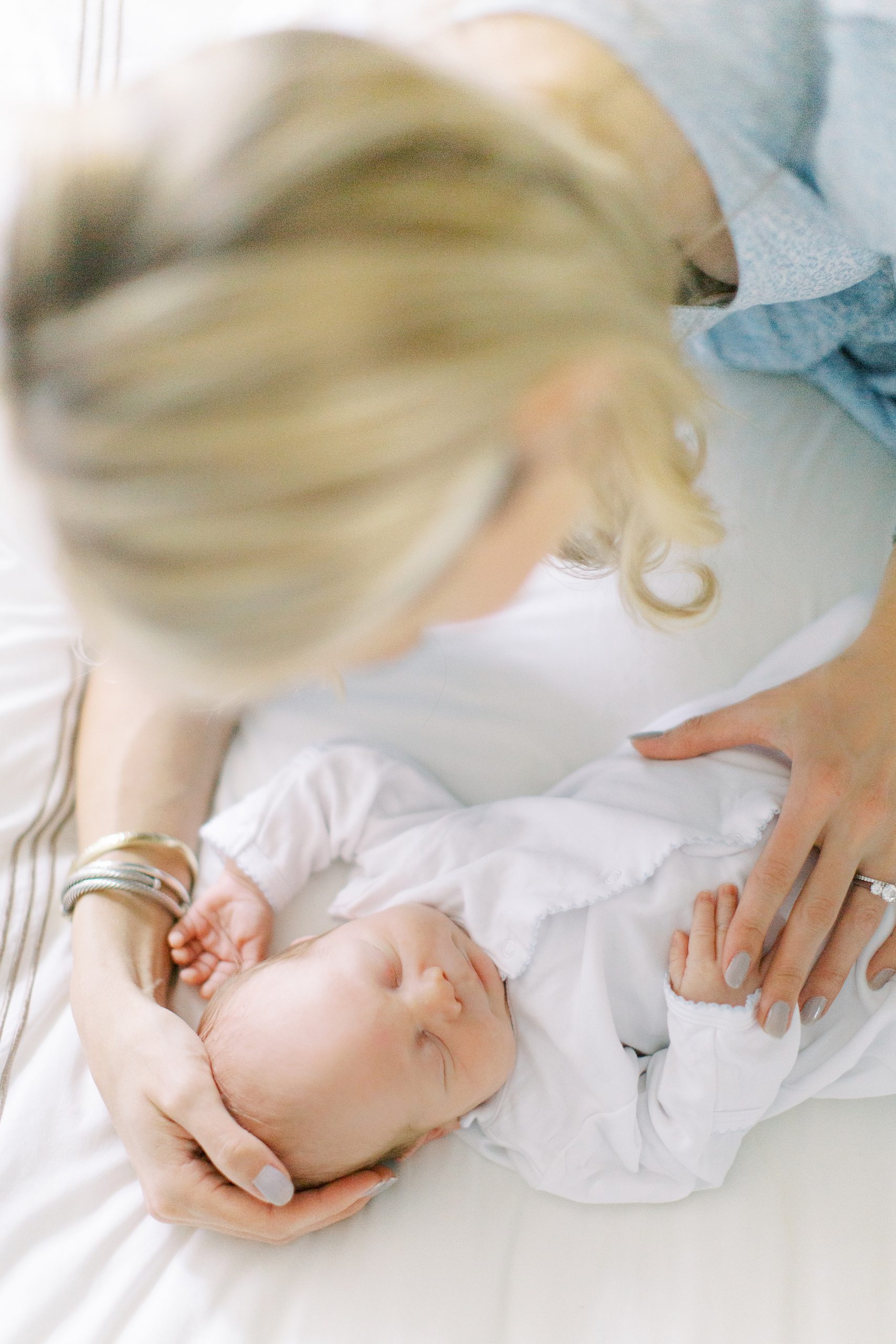 mom snuggles with baby on bed during Charlotte lifestyle newborn session