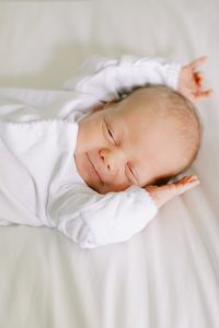 baby stretches on bed during Charlotte lifestyle newborn session