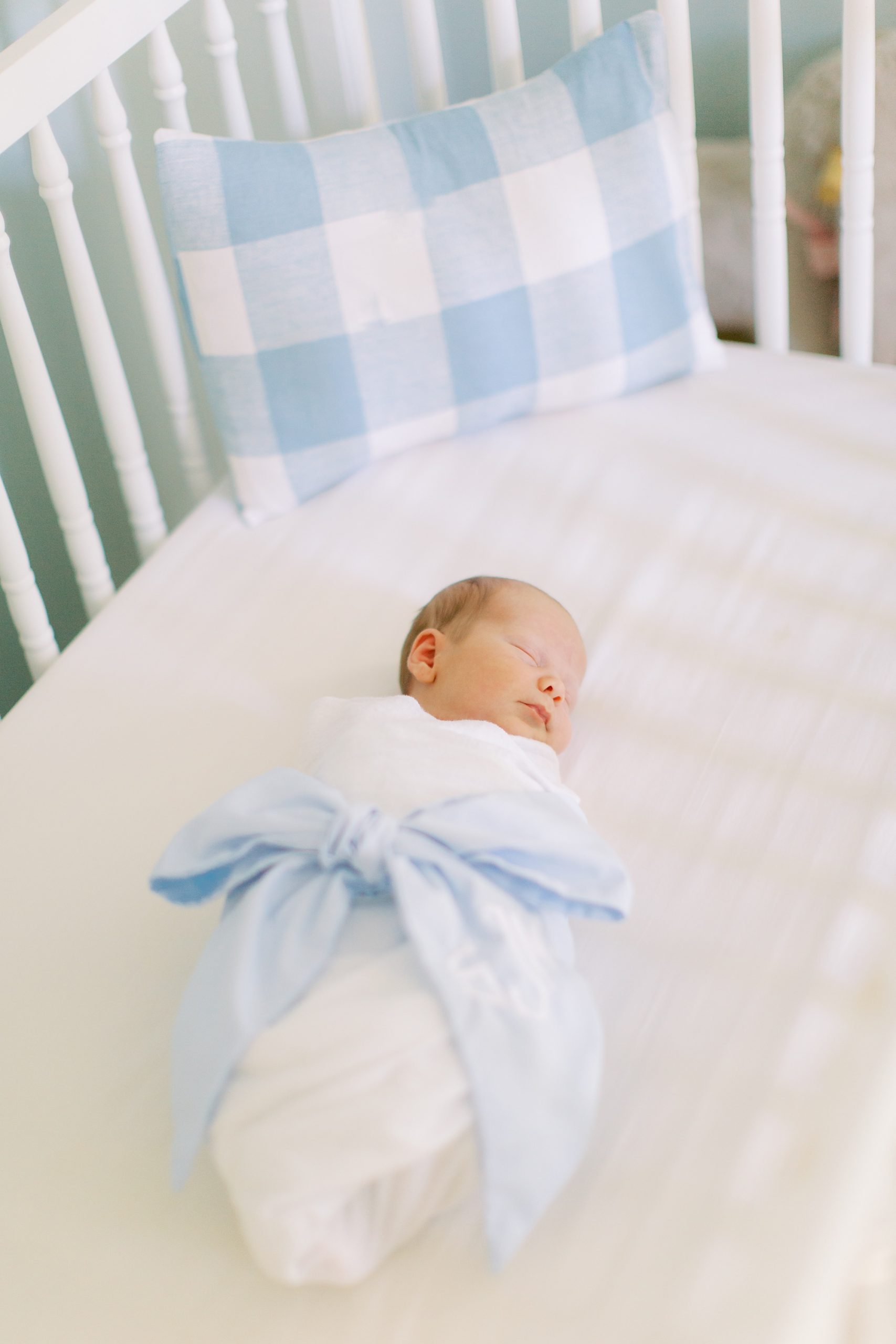 baby lays in crib with blue bow