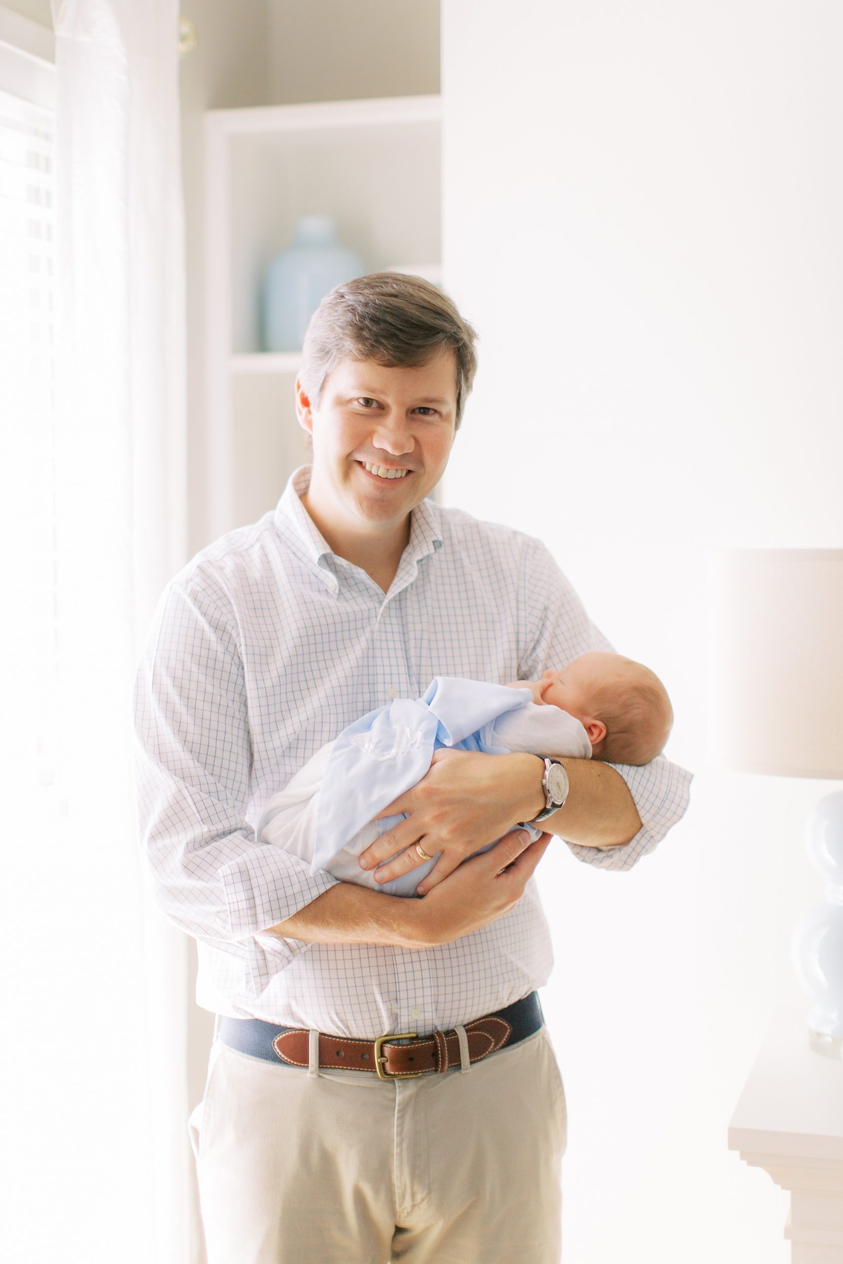 dad holds newborn baby boy during Charlotte lifestyle newborn session