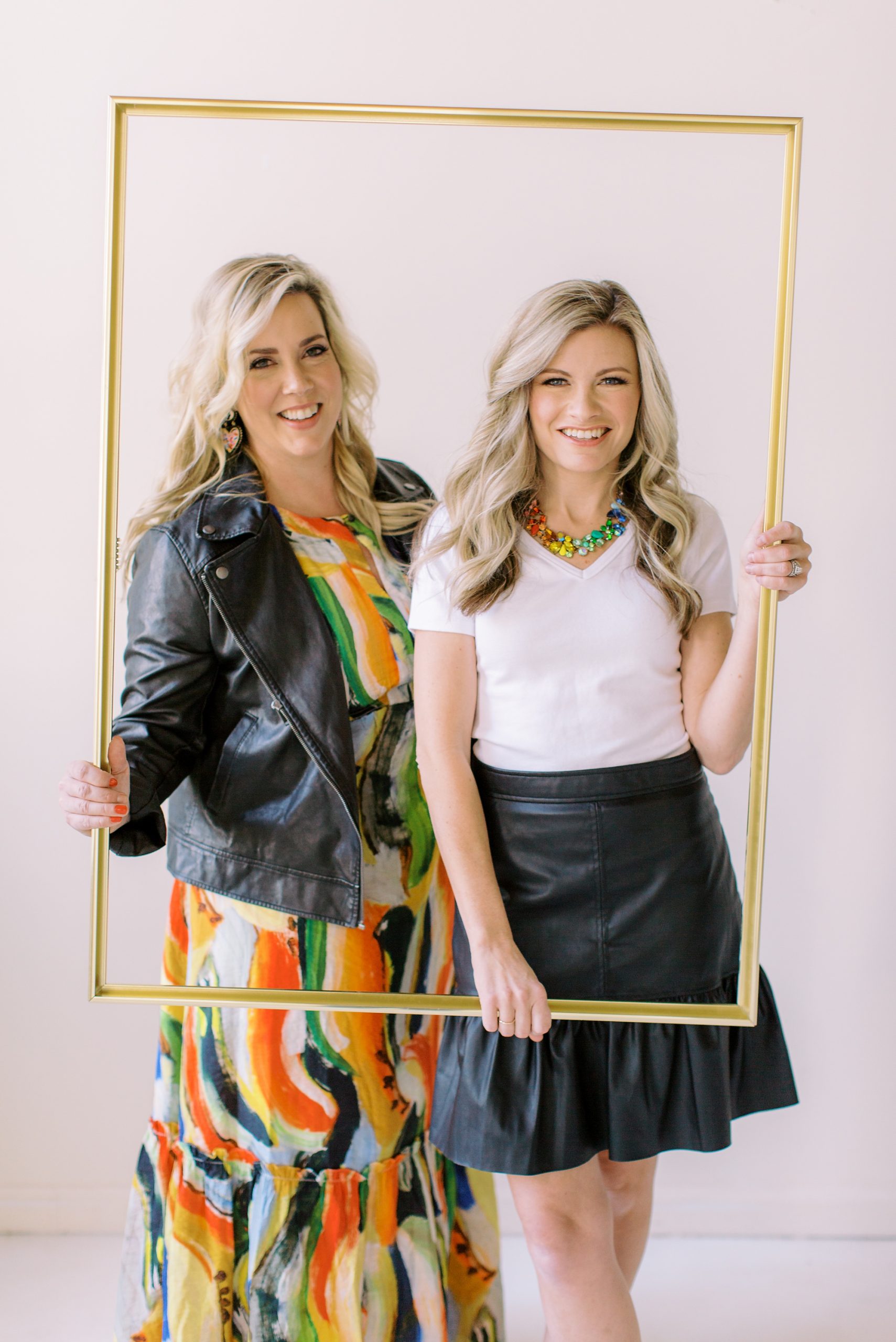 Charlotte NC wedding planners at McLean Events hold gold frame in front of themselves