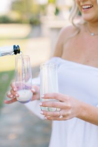 bride holds champagne glasses during Charlotte engagement photos