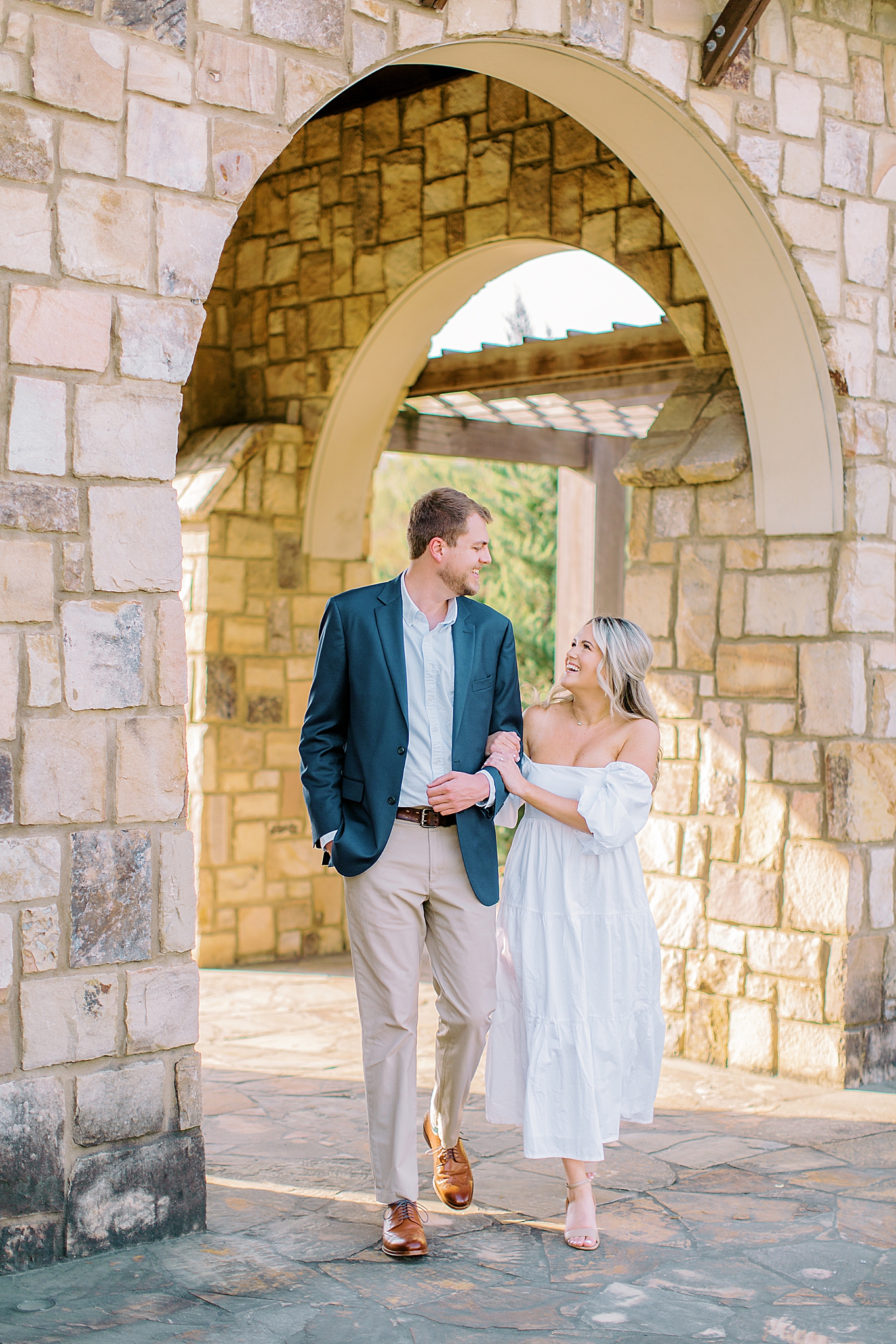 bride and groom walk through stone arbor in Midtown Park