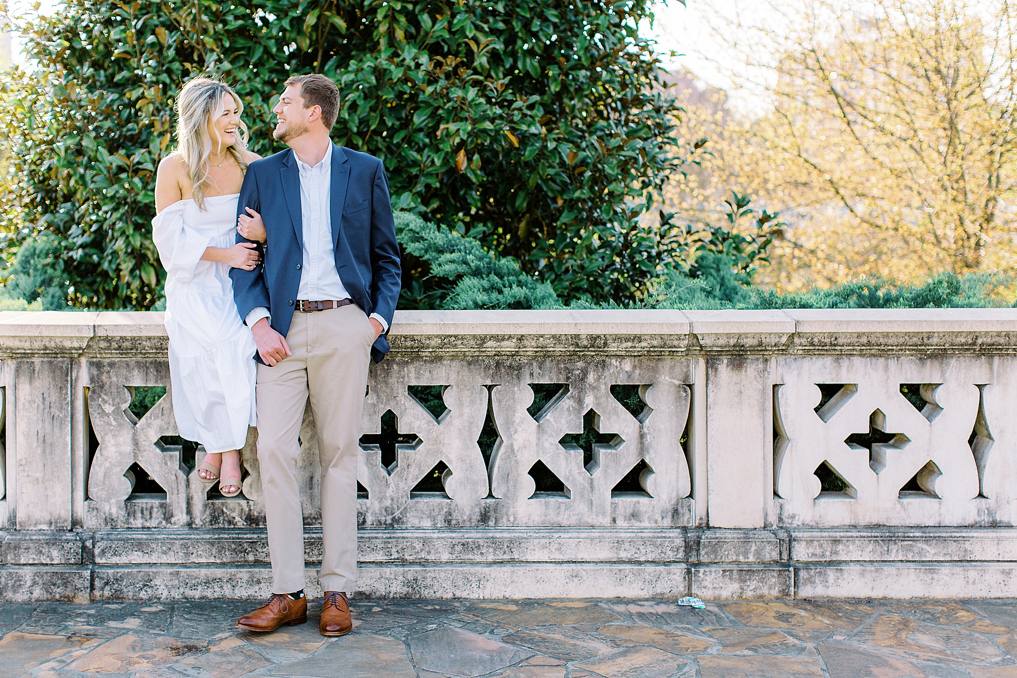 bride sits on stone wall during Midtown Park engagement session