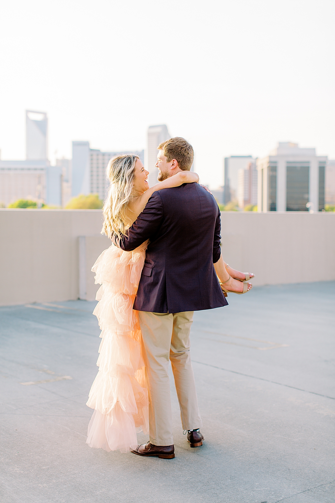 groom lifts bride during Uptown Charlotte engagement photos