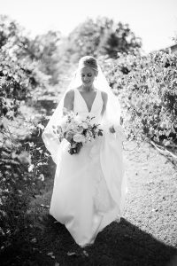 bride in classic wedding dress with veil walks through vineyard