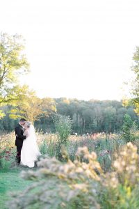 bride and groom pose in field of wildflowers at North Corner Haven