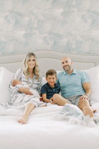 family sits on bed during Charlotte newborn session at home