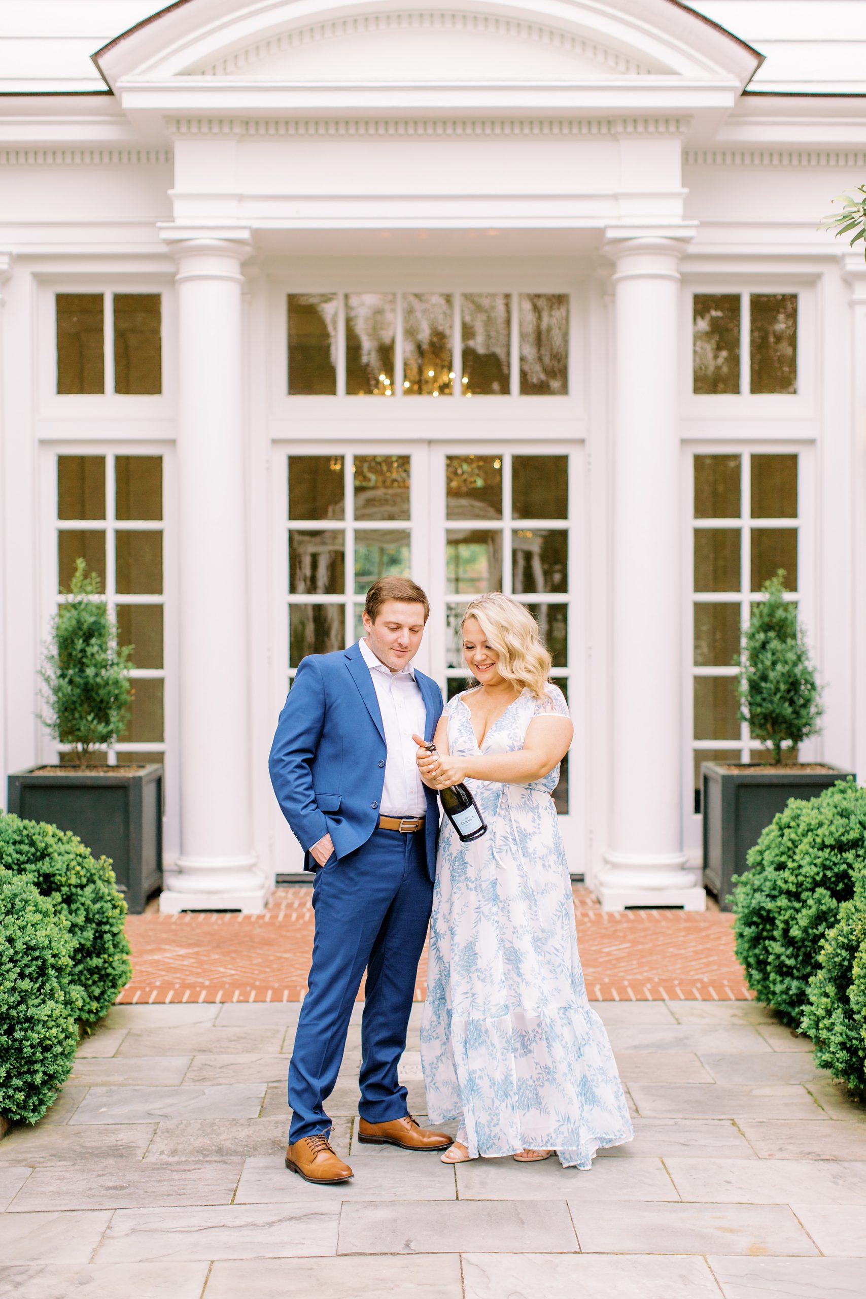 couple pops champagne during Duke Mansion engagement portraits