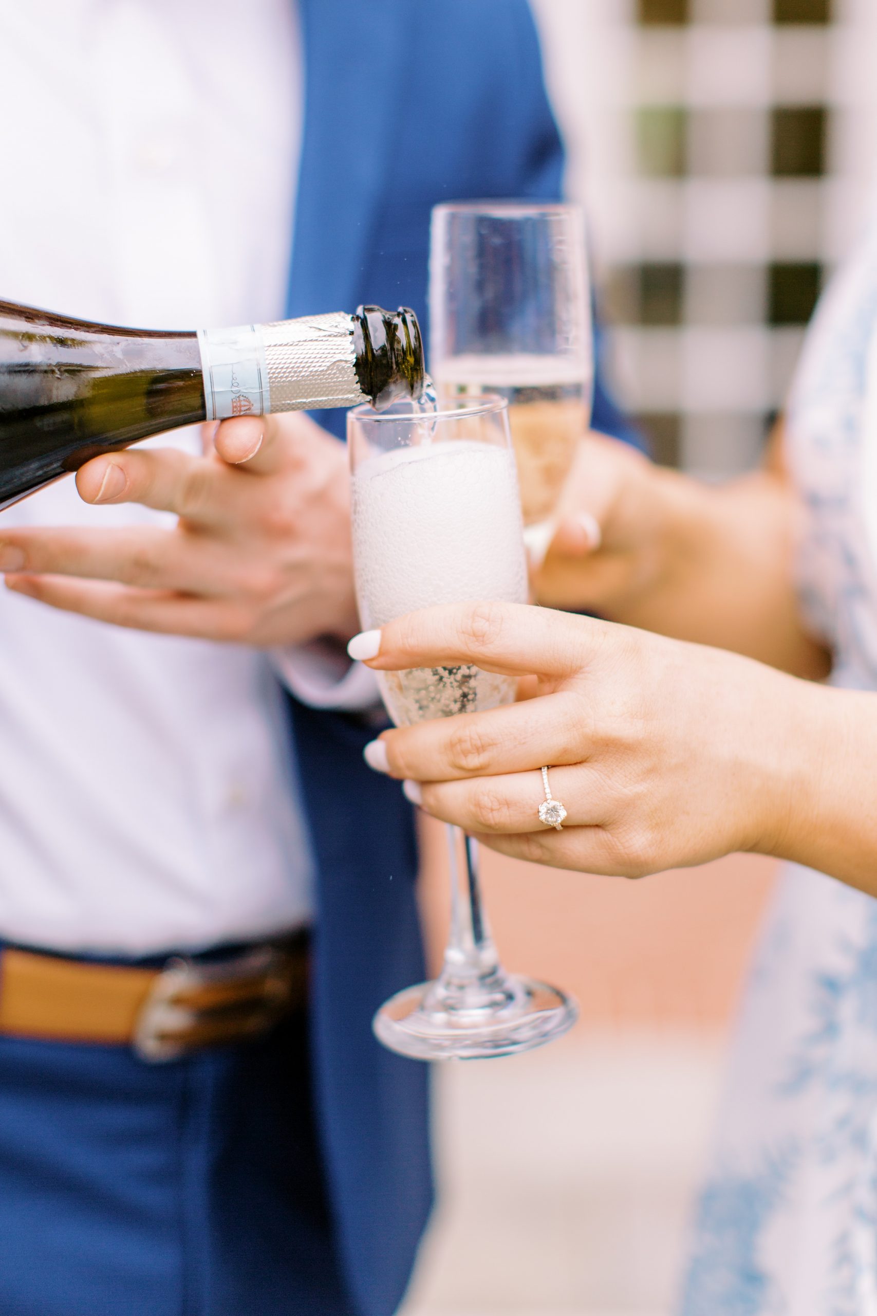 groom pours champagne into glasses for bride-to-be