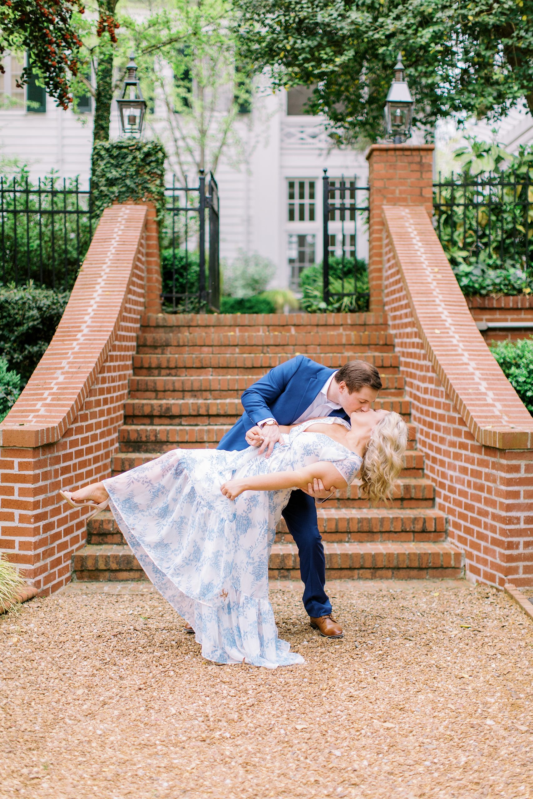 groom kisses bride, dipping her by brick steps